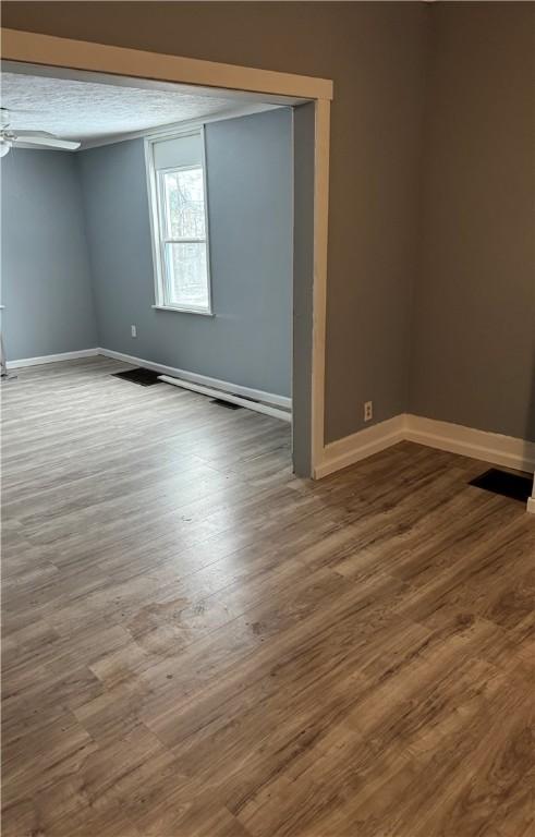 spare room featuring baseboards, wood finished floors, and a ceiling fan