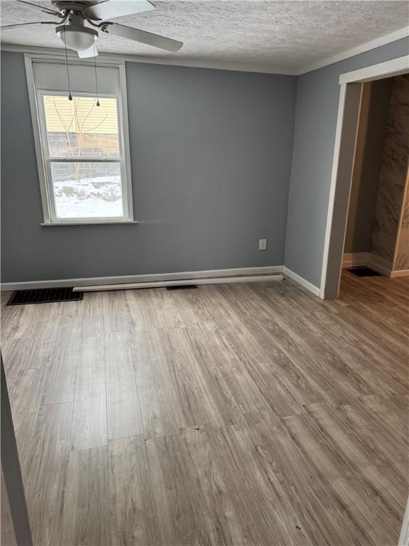 unfurnished room featuring baseboards, visible vents, wood finished floors, and a ceiling fan