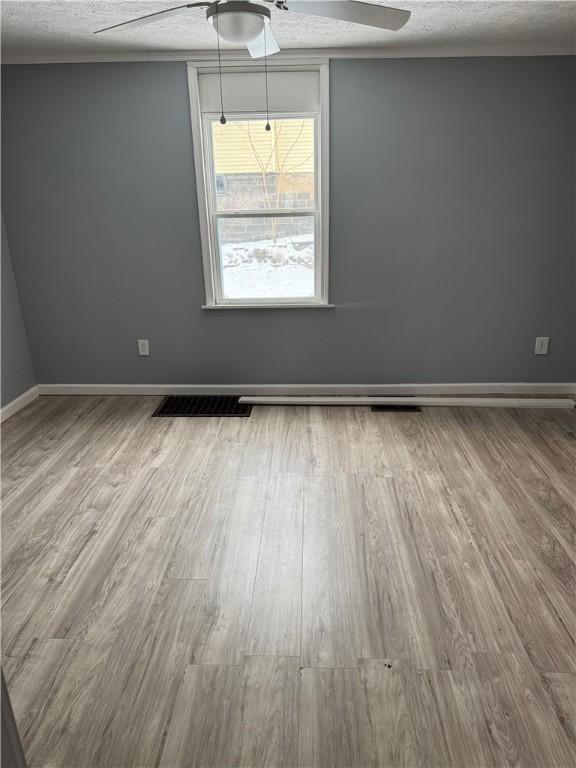 empty room featuring wood finished floors, ceiling fan, and baseboards