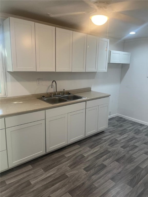 kitchen with baseboards, light countertops, white cabinets, a sink, and dark wood-style floors