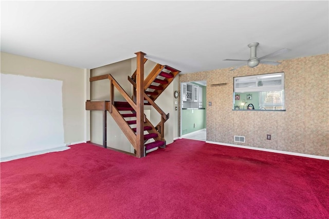 unfurnished living room with stairway, ceiling fan, visible vents, baseboards, and carpet