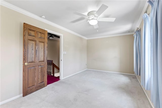 empty room featuring light colored carpet, ceiling fan, crown molding, and baseboards