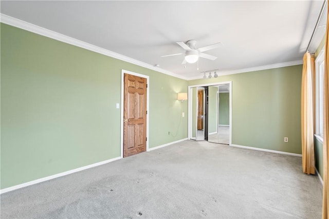 unfurnished bedroom featuring a closet, carpet, baseboards, a ceiling fan, and crown molding