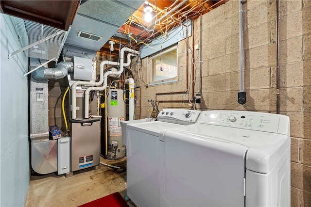 laundry area featuring visible vents, water heater, laundry area, and washer and clothes dryer