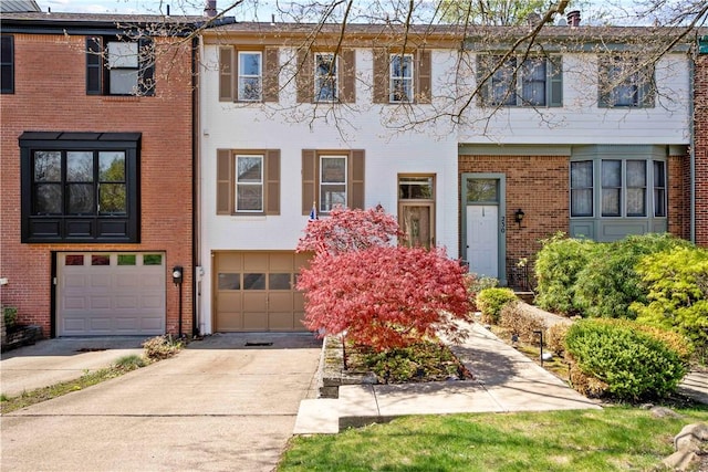 view of property featuring driveway, brick siding, and a garage