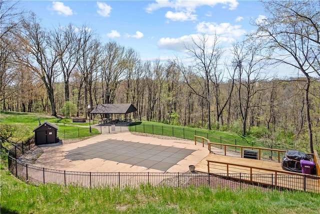 surrounding community featuring fence, a wooded view, and an outbuilding