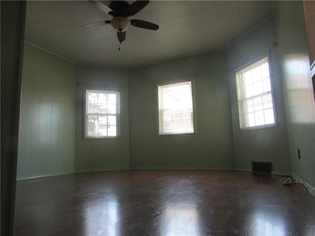 empty room featuring wood finished floors, ceiling fan, and visible vents