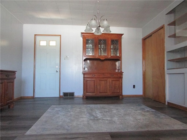 entryway featuring dark wood finished floors, visible vents, a notable chandelier, and baseboards