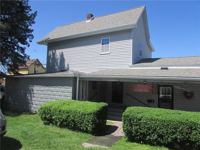 view of front of home with a porch, a front yard, a shingled roof, and a chimney