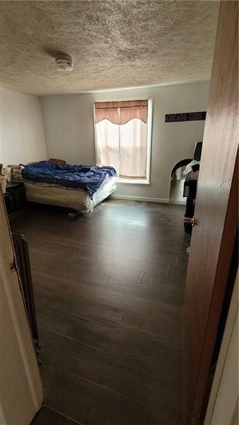 bedroom with a textured ceiling and dark wood finished floors