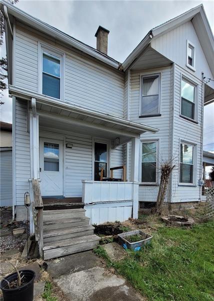 view of front facade with covered porch and a chimney