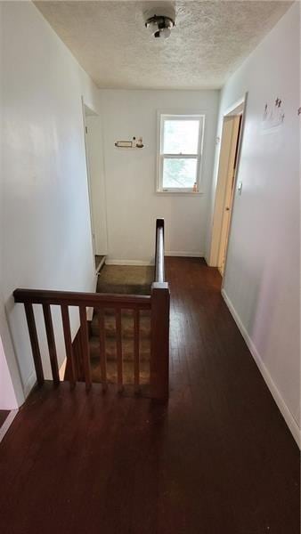 stairway featuring a textured ceiling, wood finished floors, and baseboards