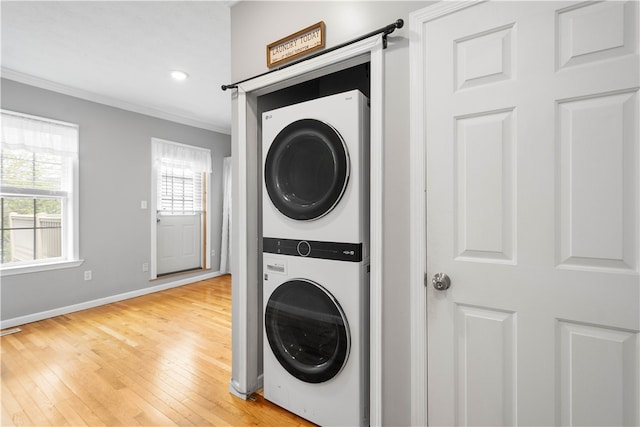 2113 Wharton St, South Side, PA 15203 - clothes washing area featuring stacked washer / dryer, light wood-style flooring, crown molding, baseboards, and laundry area