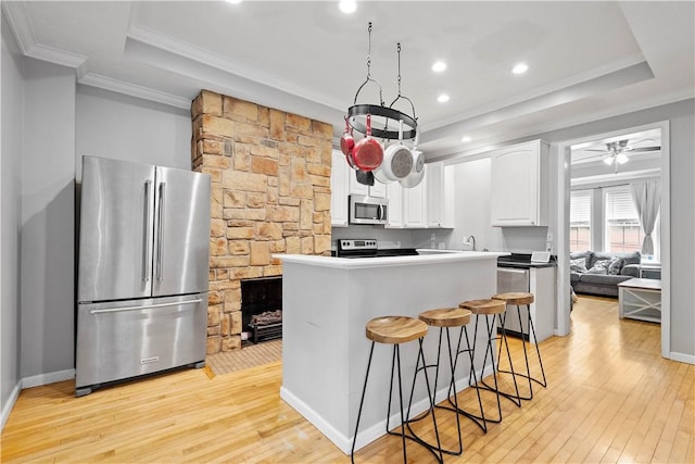 2113 Wharton St, South Side, PA 15203 - kitchen featuring white cabinetry, stainless steel appliances, a tray ceiling, light wood-type flooring, and ornamental molding