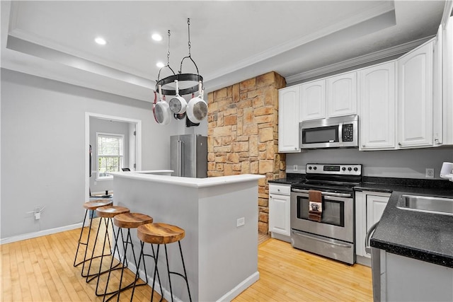 2113 Wharton St, South Side, PA 15203 - kitchen with white cabinetry, a raised ceiling, stainless steel appliances, a kitchen island, and light wood-type flooring