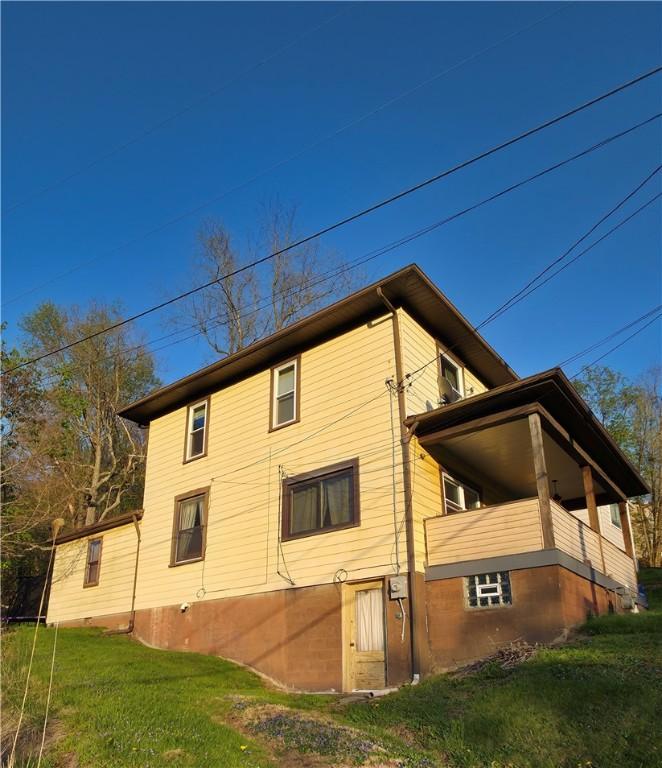 view of side of home with a yard and a balcony