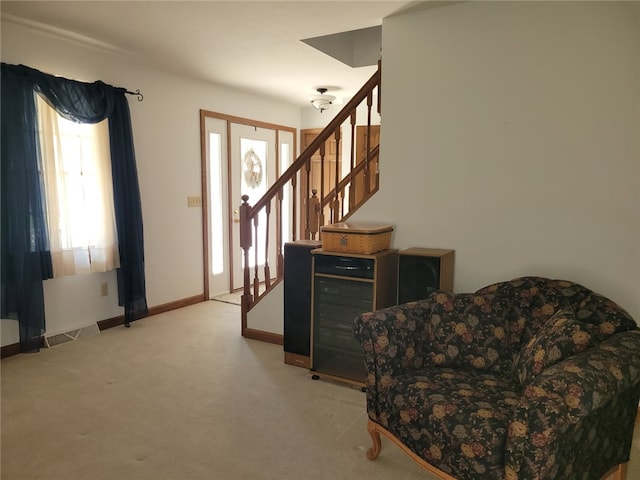 sitting room featuring visible vents, a wealth of natural light, stairs, and carpet flooring