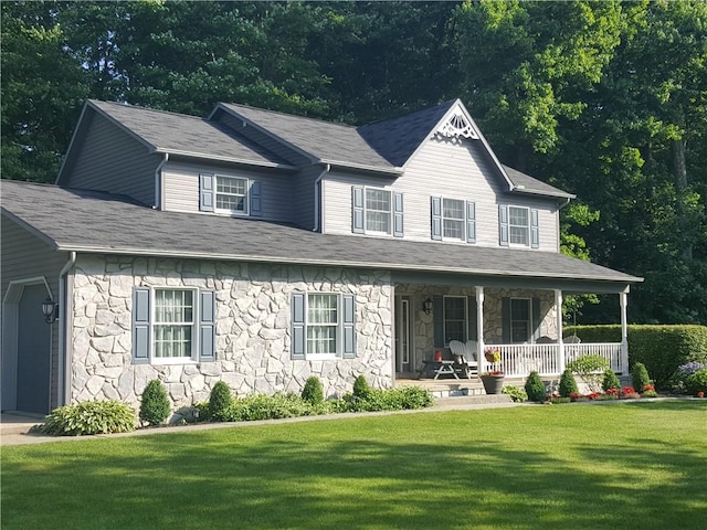 view of front of house with a front lawn, stone siding, and covered porch