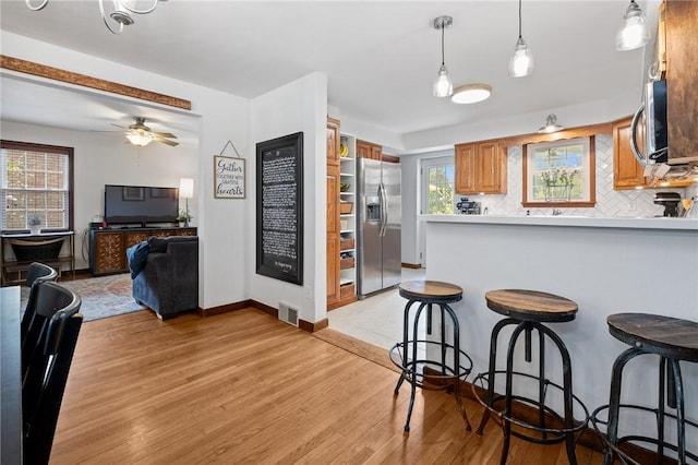 kitchen featuring light wood-style floors, appliances with stainless steel finishes, tasteful backsplash, and visible vents