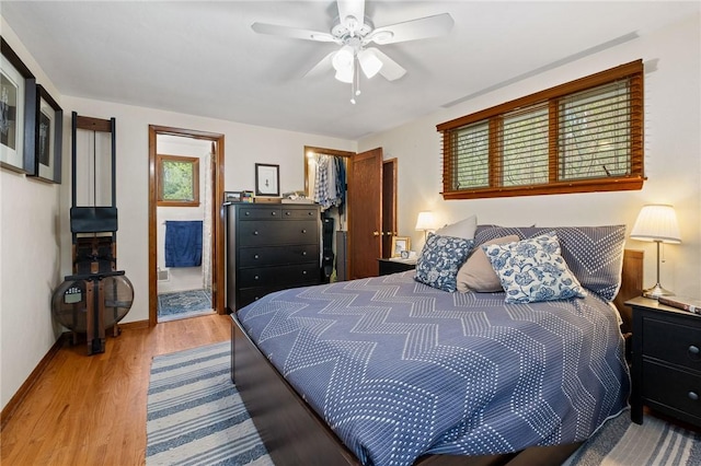bedroom featuring a walk in closet, baseboards, wood finished floors, ensuite bathroom, and a closet