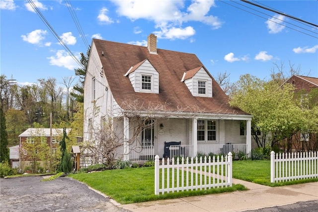 cape cod-style house featuring a fenced front yard, brick siding, a front yard, a chimney, and covered porch