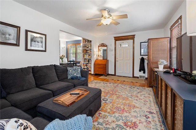 living room featuring a ceiling fan, light wood finished floors, and visible vents