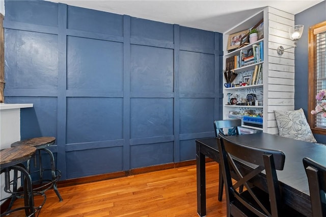 home office featuring light wood-type flooring and a decorative wall