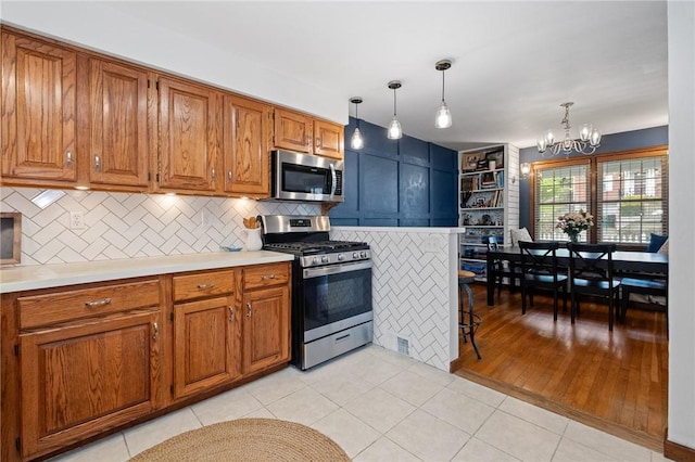 kitchen featuring light countertops, a notable chandelier, brown cabinets, and stainless steel appliances