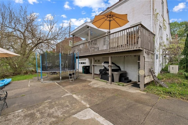 rear view of house featuring brick siding, a trampoline, and a deck