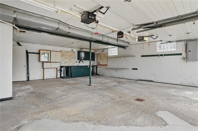 garage with concrete block wall, a garage door opener, and electric panel