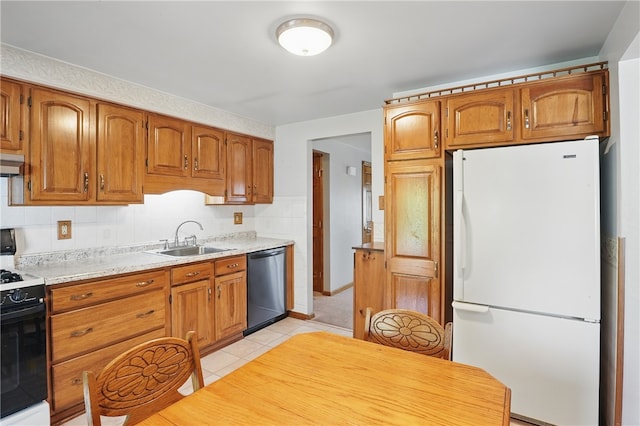 kitchen featuring freestanding refrigerator, black range with gas cooktop, light countertops, a sink, and dishwasher