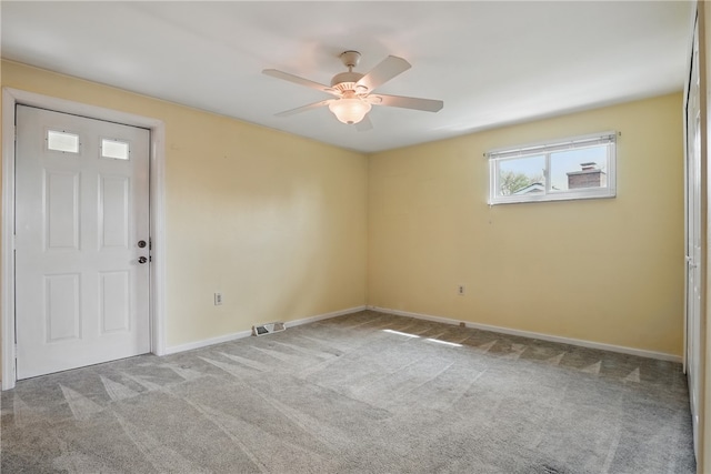 carpeted spare room featuring baseboards, ceiling fan, and visible vents
