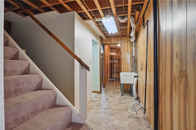 stairway featuring wooden walls