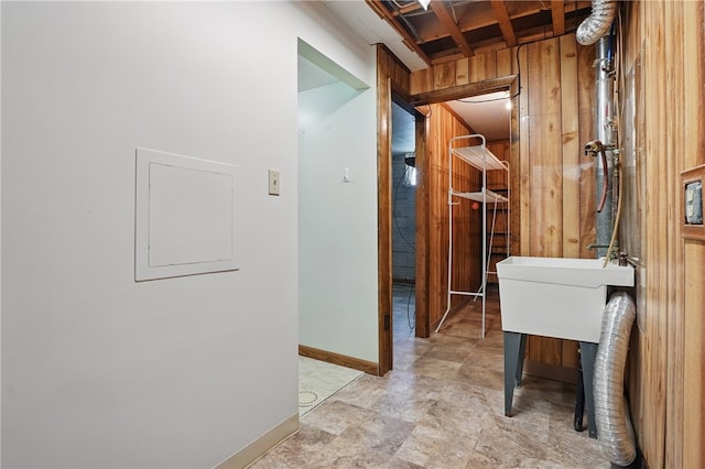 corridor featuring baseboards and wood walls