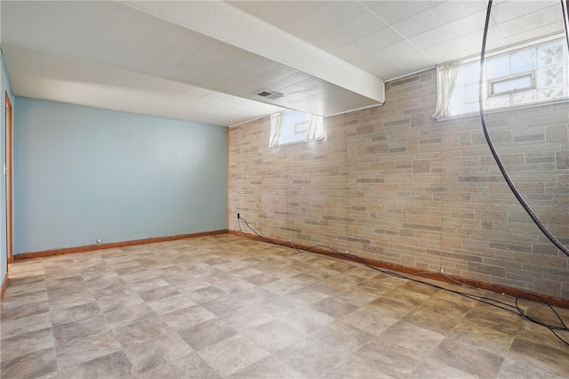 basement with baseboards, brick wall, and visible vents