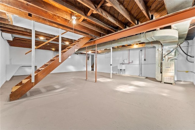unfinished basement featuring heating unit, a sink, and stairway