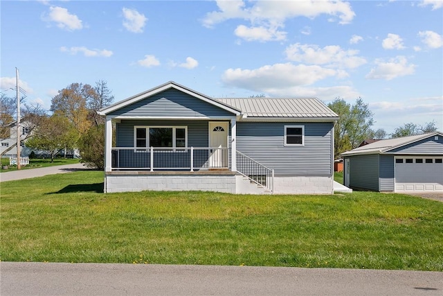 manufactured / mobile home with a detached garage, a porch, metal roof, and a front yard