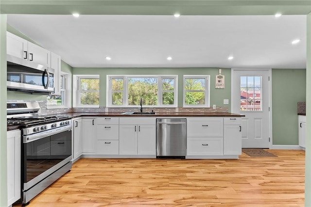 kitchen featuring a sink, dark countertops, light wood-style floors, and stainless steel appliances