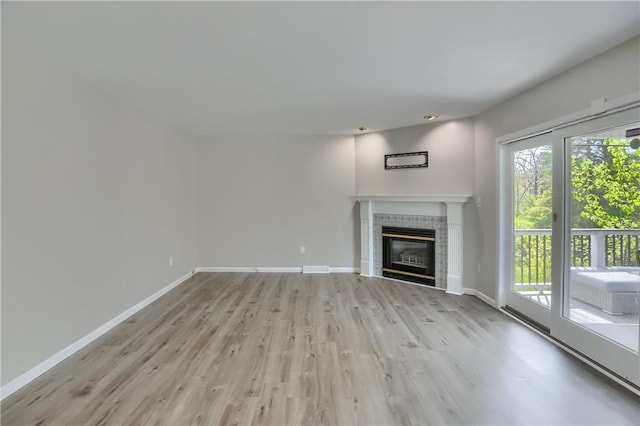 unfurnished living room featuring baseboards, a fireplace, and light wood finished floors