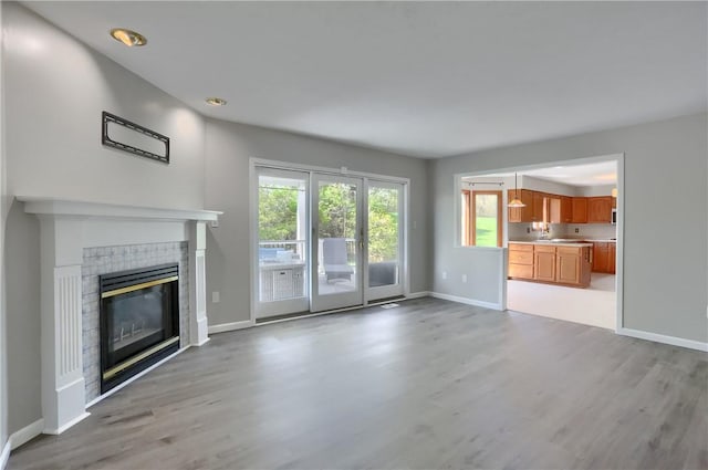 unfurnished living room with light wood-style floors, recessed lighting, baseboards, and a fireplace