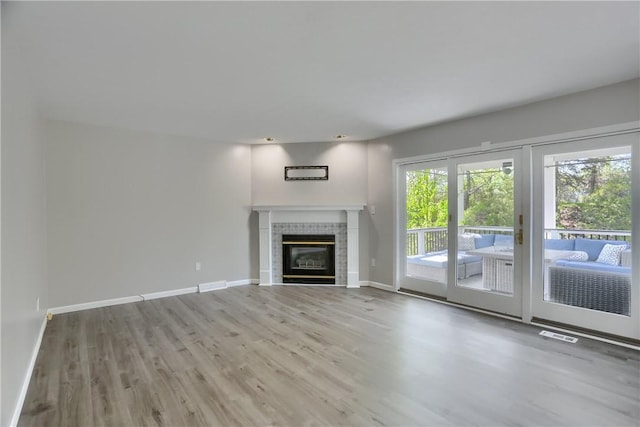 unfurnished living room with baseboards, wood finished floors, and a fireplace