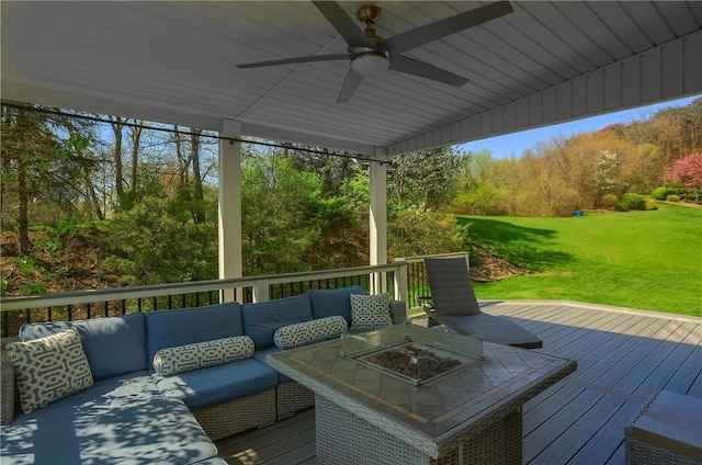 wooden deck featuring a yard, ceiling fan, and an outdoor living space with a fire pit