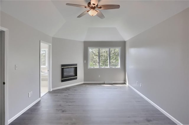 unfurnished living room with ceiling fan, dark wood finished floors, a glass covered fireplace, lofted ceiling, and visible vents