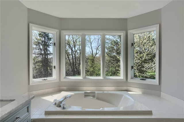 bathroom featuring a healthy amount of sunlight, a garden tub, and vanity