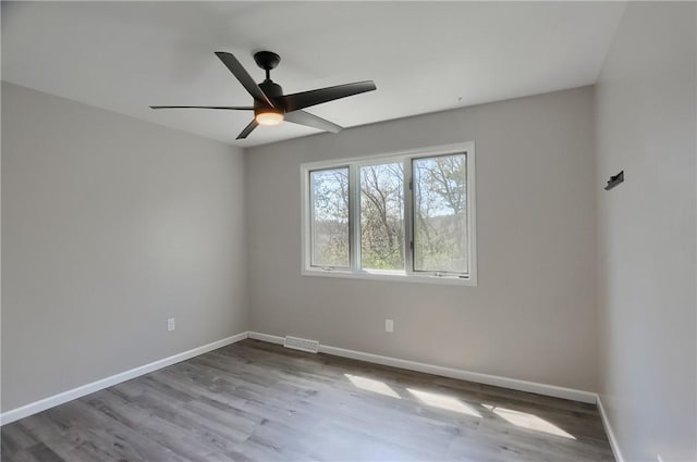 unfurnished room with baseboards, a ceiling fan, wood finished floors, and visible vents