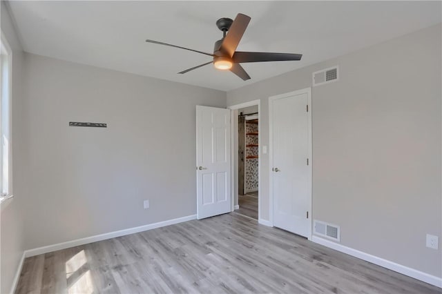 unfurnished bedroom featuring visible vents, light wood-style flooring, ceiling fan, and baseboards