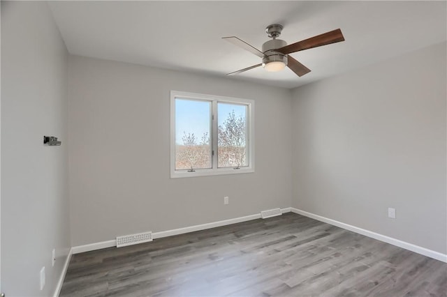 empty room with a ceiling fan, baseboards, visible vents, and wood finished floors