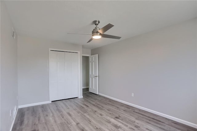 unfurnished bedroom with a ceiling fan, baseboards, wood finished floors, visible vents, and a closet