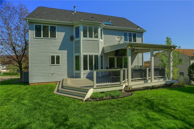 rear view of property with a lawn, a deck, central AC, and roof with shingles