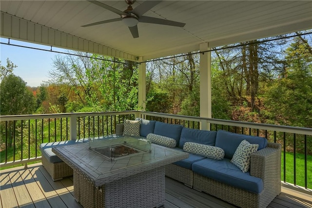 wooden deck featuring an outdoor living space with a fire pit, a ceiling fan, and a forest view